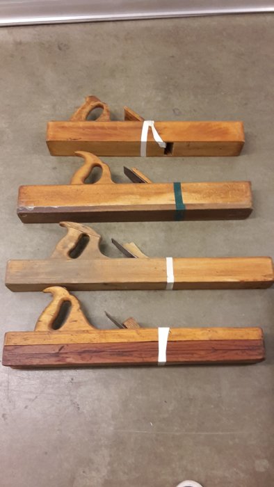 Trähyvlar med olika storlekar och profiler, säkrade med tejp, ligger på golv.