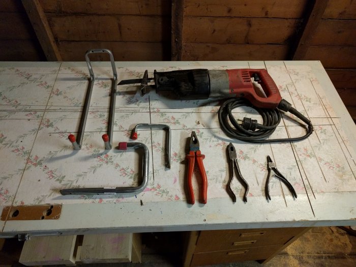 Verktyg på bord: två handsågar, tigersåg, Knipex tång och ytterligare två tänger.