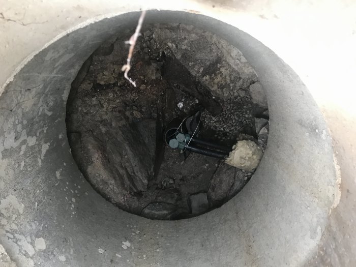 Insyn i en potentiellt torr stenbrunn med ejektorpump och synlig grund.