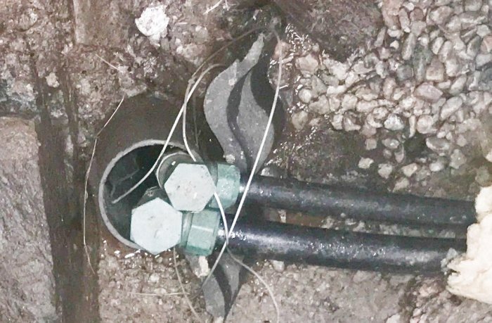 Närbild på en plastgenomföring med flera kablar och en grön skruv genom sten och isolering.