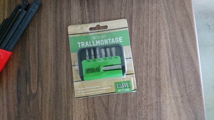 Ett förpackat bits-kit för trallmontage från Essve på ett träbord, innehållande bitssortiment för terrasskruvar.