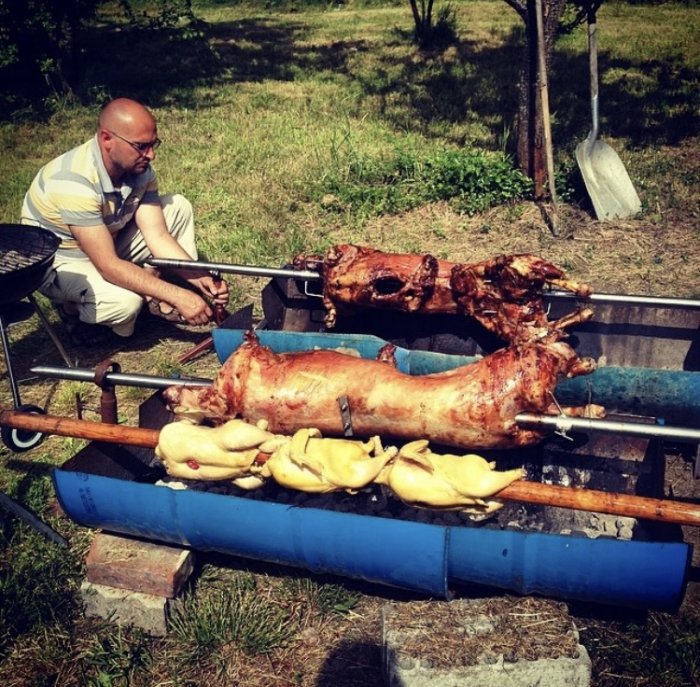 Man griller helstekt lamm och kyckling utomhus på stort spett.