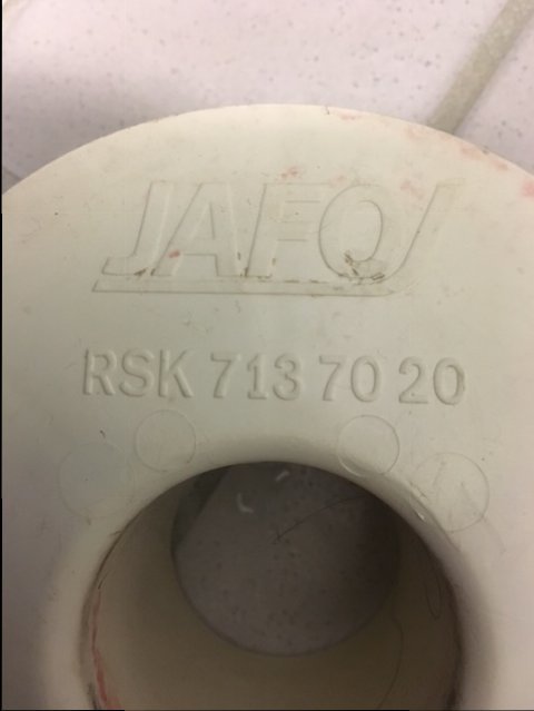 Närbild av ett vitt avloppslock med märkningen "JAF" och "RSK 713 70 20" tryckt på ovansidan.