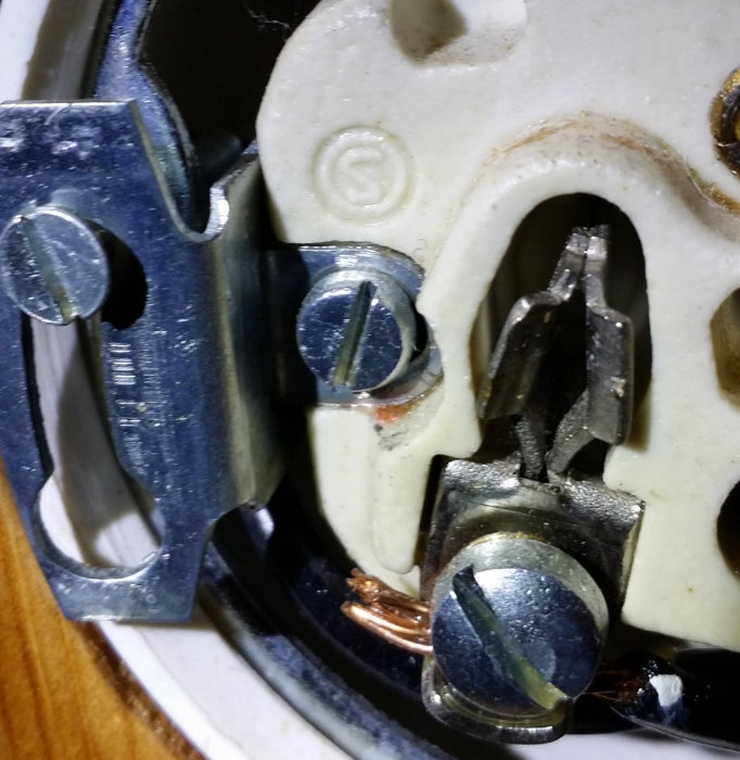 Närbild på ett gammalt, oidentifierat elektriskt uttag med symbolen 10/250 inuti utan påtaglig spänning.