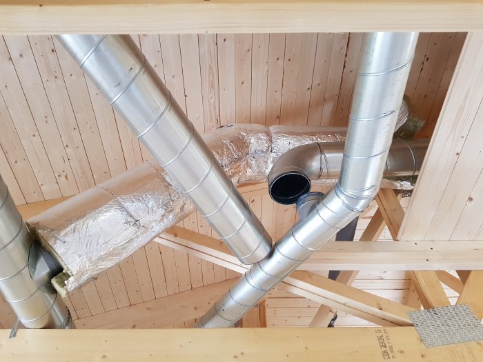 Ventilationsrör monterade i takstolar med isolering i ett pågående byggprojekt.