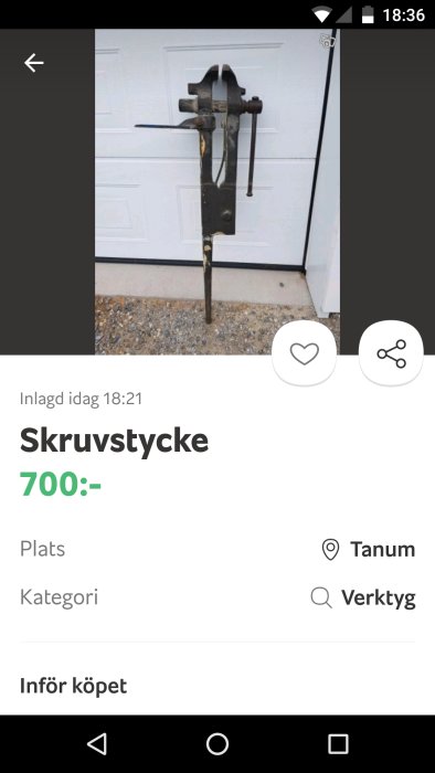 Gammalt skruvstycke framför vit garageport, använt skick, till salu för 700 kr.