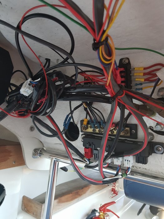 Elektrisk installation med trassliga kablar och säkringspanel i en båt.