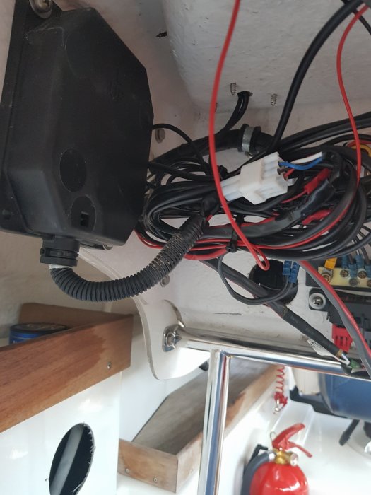En samling av trassliga kablar och elektriska komponenter monterade vid en båtvägg.