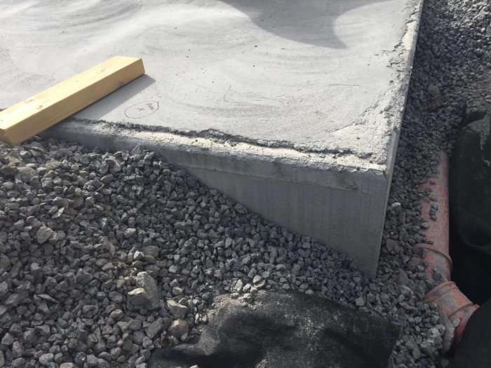 Ny betongplatta som inte linjerar med kantelement, skapa ett mellanrum, med synlig frigolit och grus.
