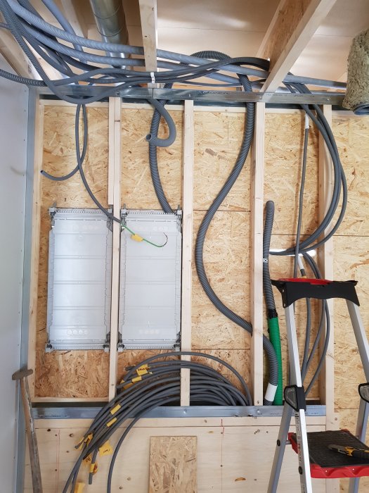 Installation av FTX-system med synliga reglar, elledningar och ventilationsrör på en OSB-vägg.