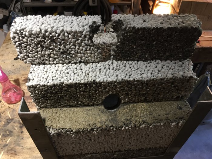 Staplade betongblock med synligt bruk i mitten väntar på att härda i en verkstadsliknande miljö.
