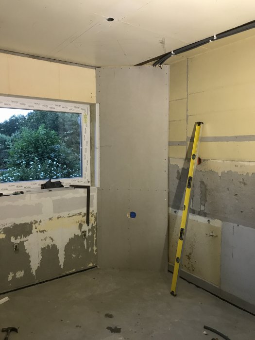 Pågående köksrenovering med en markerad plats för takintegrerad fläkt, omgiven av omålade väggar och en nivåställare.