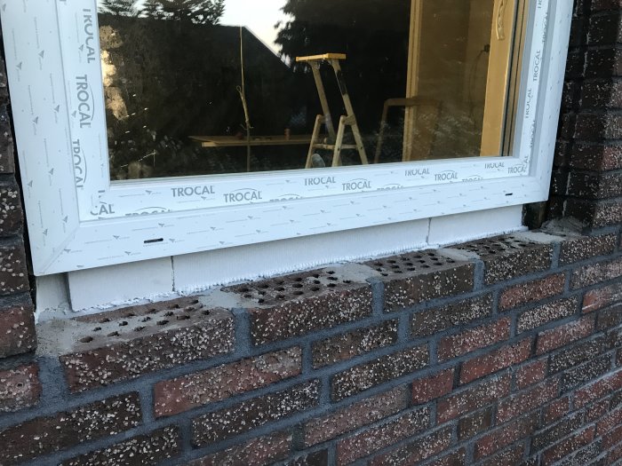 Nytt mindre fönster i tegelhus med synlig lättbetong och isolering kring fönsterkarm.
