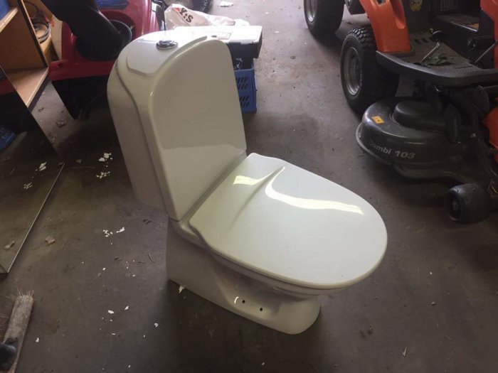 Begagnad toastol med dubbelspolning placerad i garage med gräsklippare i bakgrunden.