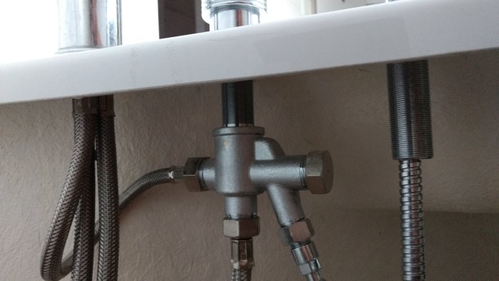 Metallventil ansluten till duschslang och bubbelbadsmunstycken under badkarskant, problem med vattenflödesreglering.