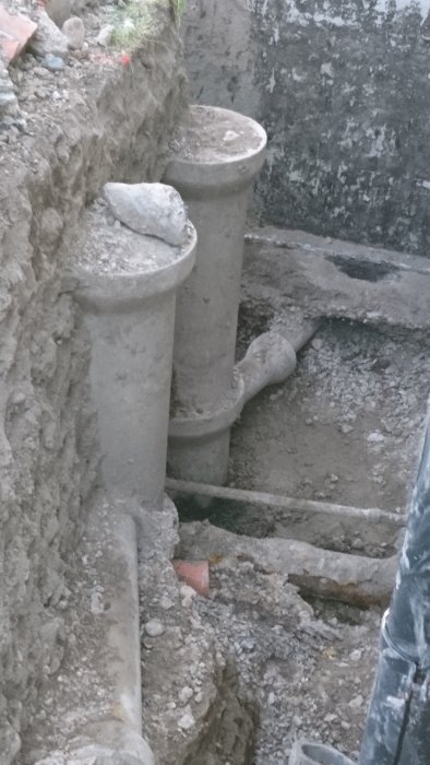Avloppsrör och betongbrunn i grävd grop som visar potentiella avloppsproblem.
