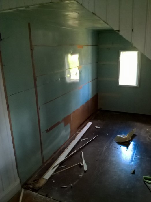 Delvis nedriven interiör av en kattvind med flis och träskräp på golvet, redo för renovering.