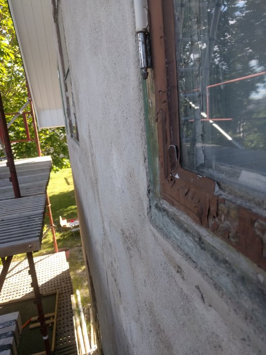 Bild på ett renoveringsprojekt av en fasad från 1930-talet med synlig fönsterkarm och avsaknad av putslag.