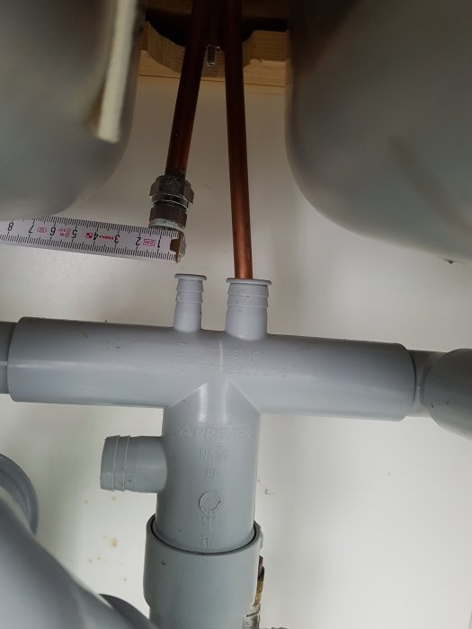 VVS-installation under diskbänk med T-koppling och mätare vid kopparrör.