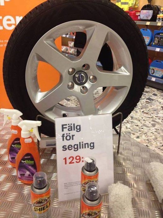 Bilfälg på display med skylt "Fälg för segling" och priset 129, flankerad av rengöringsprodukter.