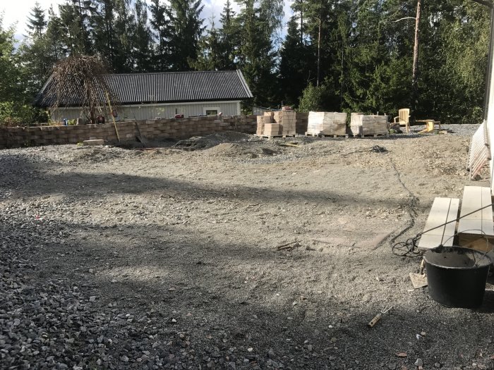 Tomt med spräckt berg och grushögar redo för fiberinstallation och läggning av markplattor.