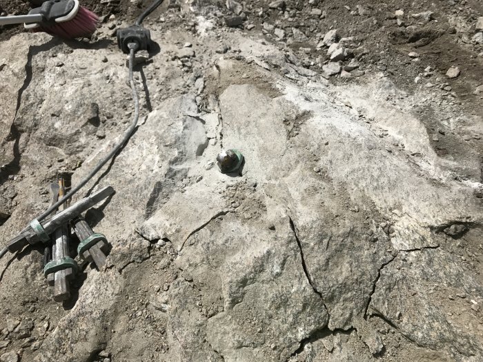 Spräckt berggrund med kablar och verktyg inför fiberinstallation.