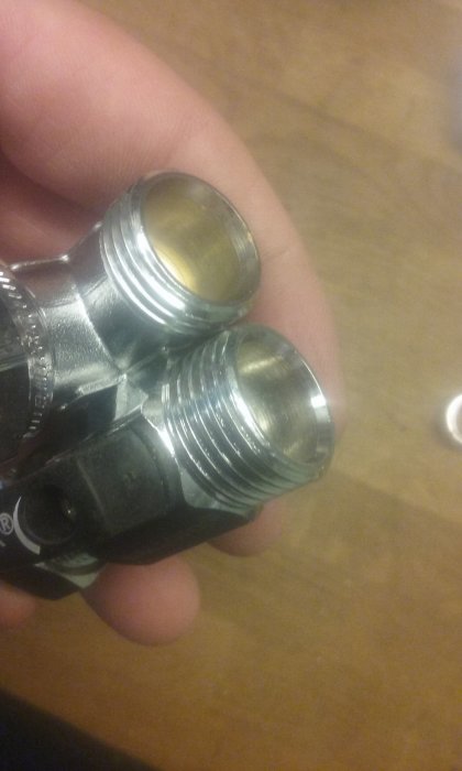 Närbild på en hand som håller Vatette och Ballofix kopplingar med och utan planadapter.