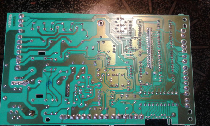 Kretskort från en tvättmaskin med synliga lödningar och kretsbanor, fokus på området nära den svagare lödningen.