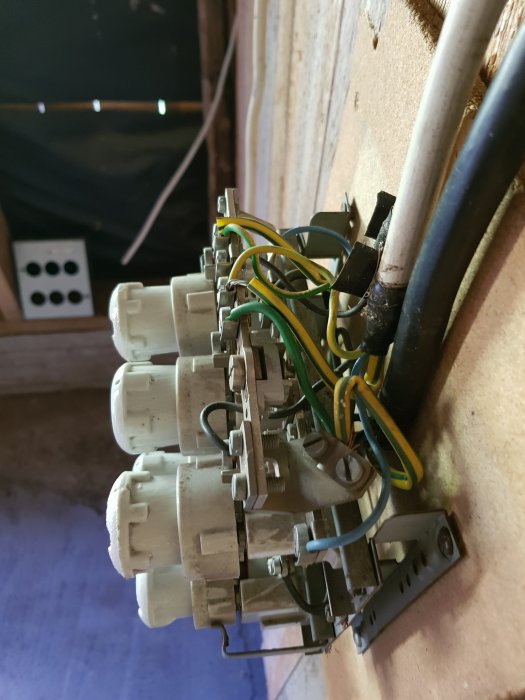 Gammal 3-fashandske i metall monterad på vägg med kopplingsledningar och avbruten strömförsörjning.