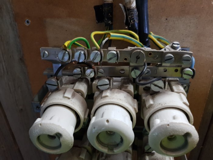 Elcentral med tre säkringshus kopplade till skruvar och faskablar som diskuteras för fastsättning.