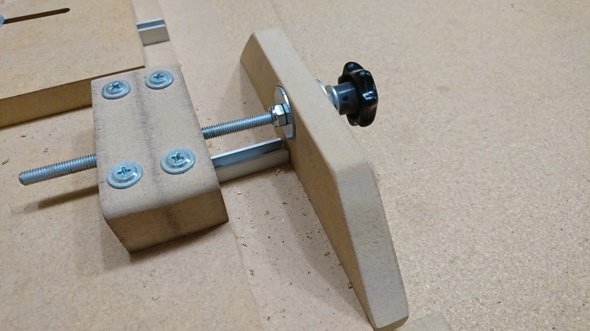 Justerskruv med svart vred monterad på MDF-bitar, för byggprojekt.