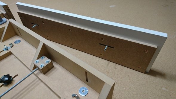 Snickerikonstruktion med MDF-skivor, justerskruvar, vingmuttrar och melaminskivor på arbetsbord.