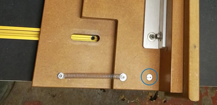 Verktygsfjäder på arbetsbänk med en inringad skruv på högerkanten.