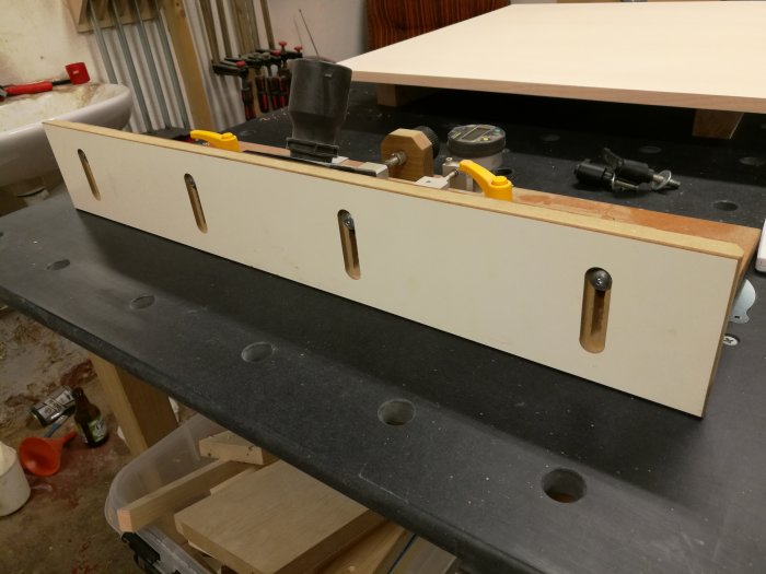 Verktygsfäste i MDF-skiva med avlånga hål och skruvar, använt i en snickarverkstad.