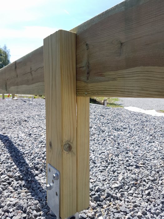 Trästolpe förstärkt med metallbeslag skruvat i sidan under bärlina för byggprojekt.