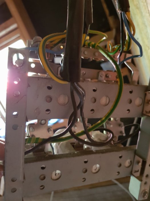 Elektriska kablar och anslutningar monterade på metallreglar i ett byggprojekt.