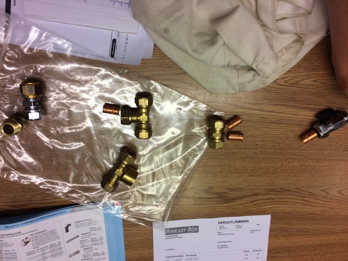 Duschblandarkomponenter och rörkopplingar på bord med installationsanvisningar och packmaterial.