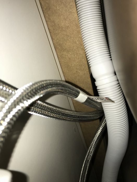 Röranslutningar under köksbänk med löstaget rör nära en blandare.