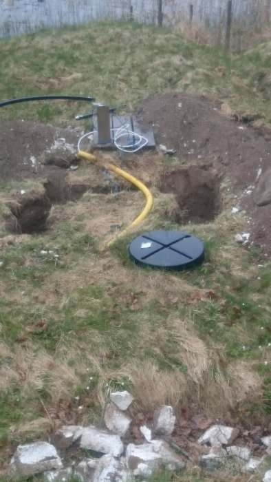 Reparerad avloppsgrop med frigolitisolering och gul elkabel till brunnpump, allting återställt.