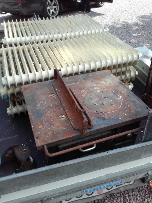 Begagnade element och en rostig vedspis som ligger på ett släp, redo att transporteras.