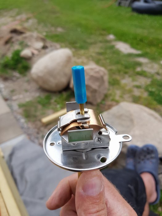 Hand håller en demonterad del av en husvagnsvärmare med en blå kabel.