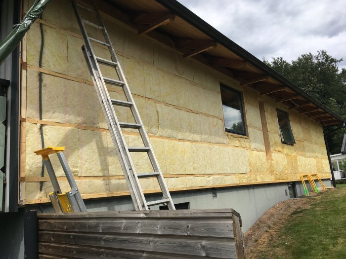 Nyisolerad yttervägg på hus med stege och byggställning.