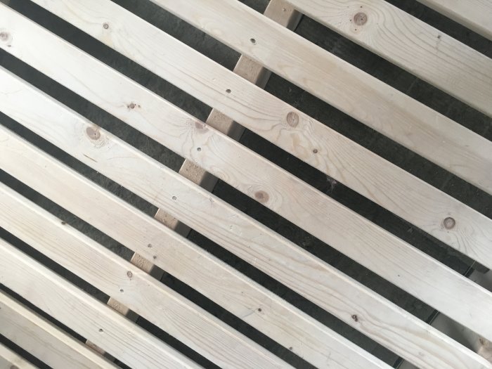 Vit glespanel gjord av smala träreglar mot en mörk bakgrund.