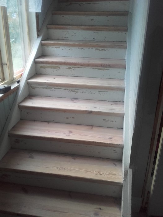 En trätrappa under renovering med nyslipade steg och vit hårdvaxolja.