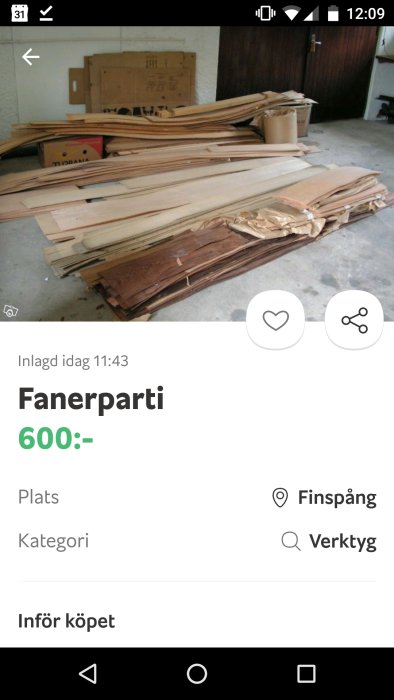 Parti av olika fanerark staplade på garagegolv med prislapp 600 kr.