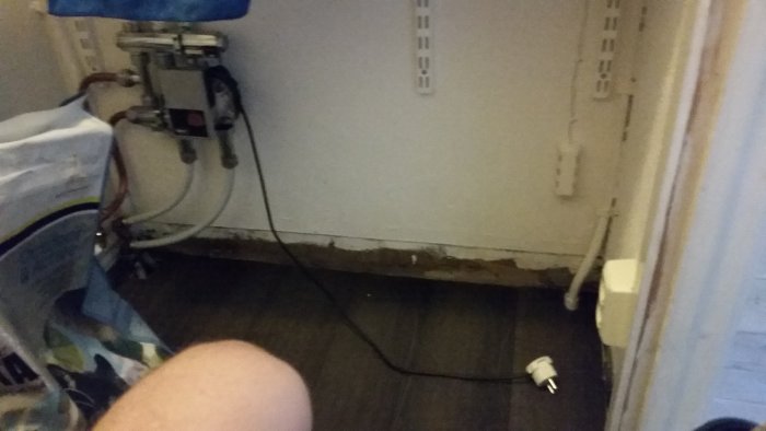 Provisorisk lösning för golvvärme med en löst hängande kabel och stickpropp på ett köksgolv.
