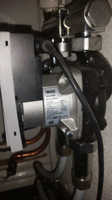 Närgransad bild på en Wilo cirkulationspump installerad i ett VVS-system med kopparledningar.