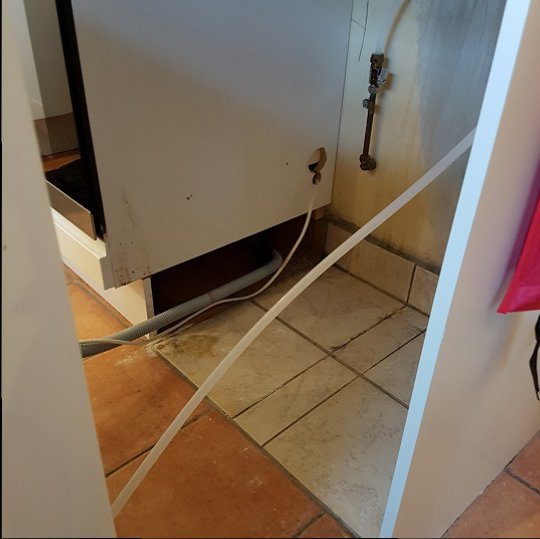 Synlig vattenslang och rör vid vit skåpdörr i kök som behöver skarvas för att nå blandaren.