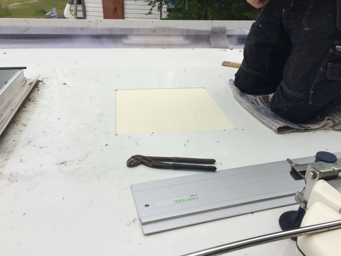 Person som monterar aircondition på husvagnstak med utmätta verktyg och skuren öppning.