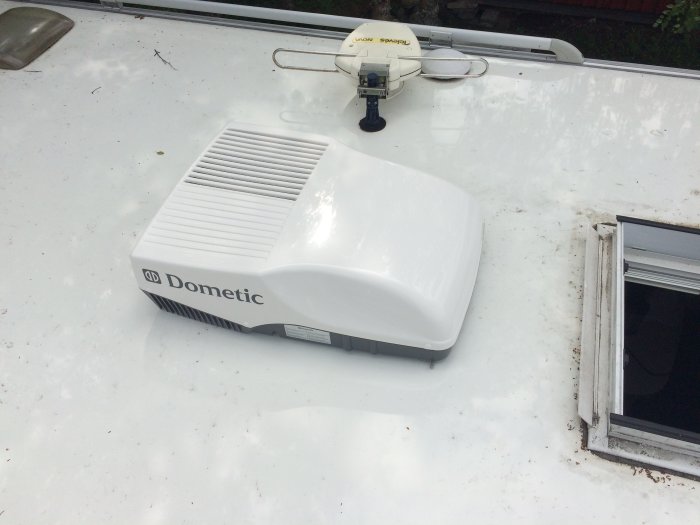 En nyinstallerad Dometic aircondition på taket av en husvagn bredvid en öppen taklucka.